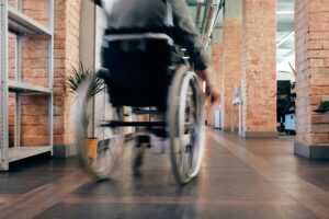 pexels-photo-4064339-4064339 Blurred motion of a person in a wheelchair moving quickly through an indoor office hallway.